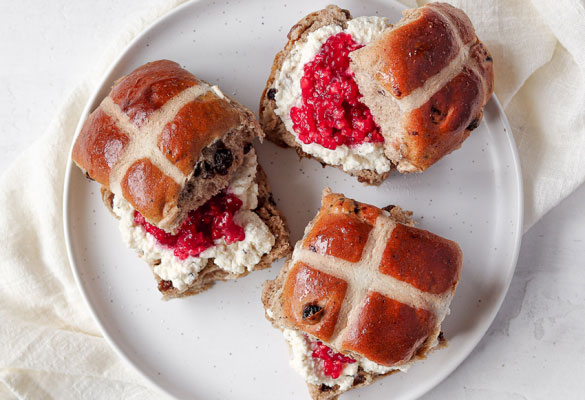 Hot cross bun topped with ricotta and raspberries