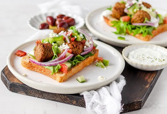 Open falalfel sandwiches on a chopping board