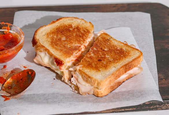 Chicken Parm grilled cheese sandwich on a chopping board