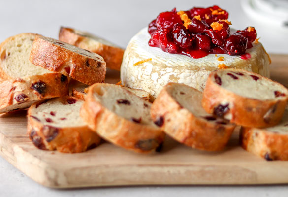 Baked Brie with Cranberry and Sea Salt French Baguette. Bread on a board with cheese