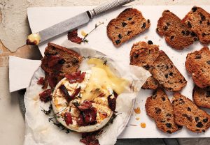 hot cross bun crostini with baked brie with pancetta, thyme, and honey on a board