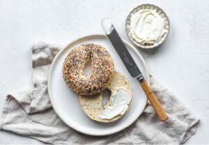 bagel on a plate with cream cheese or butter with a knife beside it on the plate